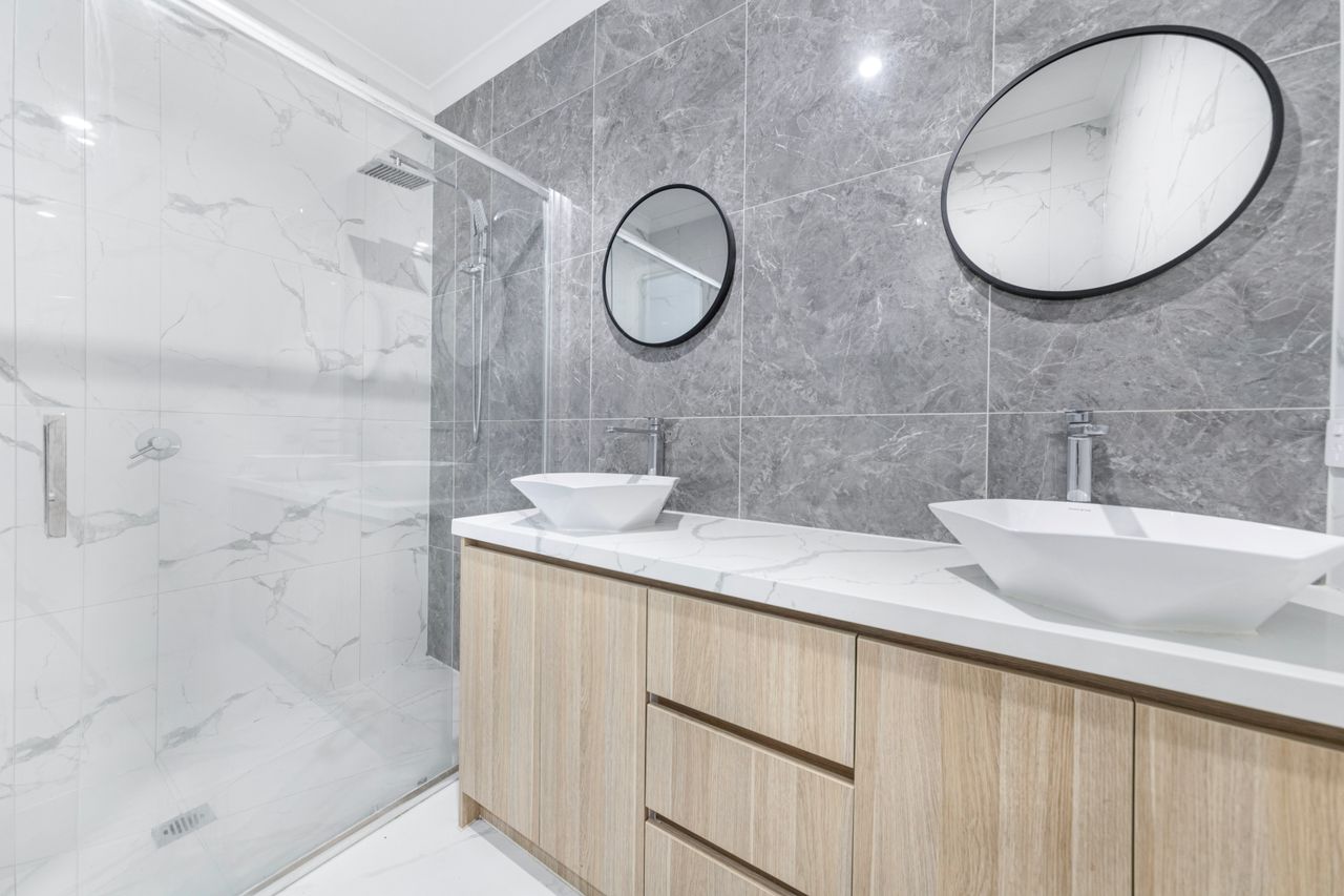The Art of Drawing Readers In: Your attractive post title goes here Stylish and elegant modern bathroom featuring double sinks, oval mirrors, and marble tiles.