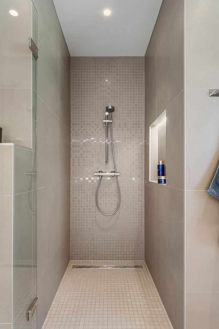 portfolio-03 Contemporary shower with glass and tiled surfaces in a minimalist bathroom.