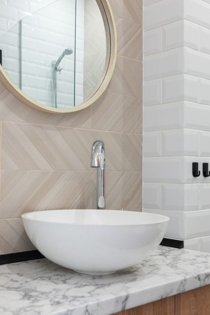 washroom-interior-with-sink-and-tap-on-counter-near-mirror-6782428 Interior of light modern restroom with sink and faucet on cabinet under mirror on tile wall